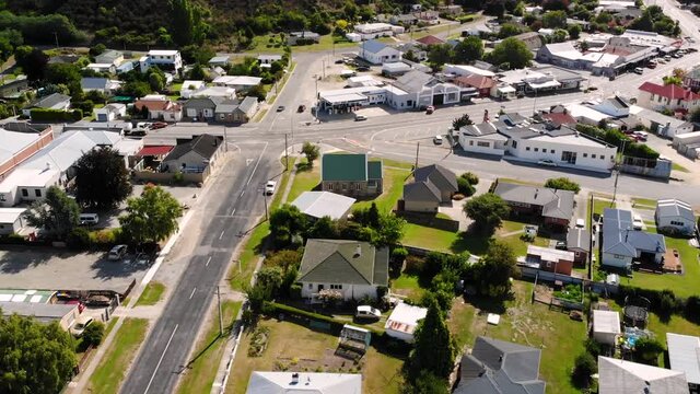 Main street in Roxburgh. Aerial orbit tilt up shot of truck passing through small town on New Zealand countryside.