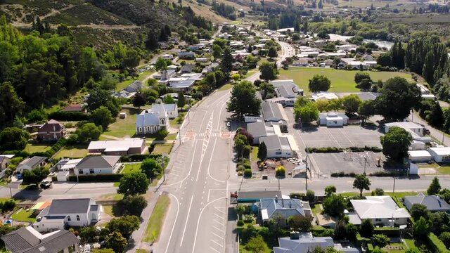 Main road in Roxburgh, New Zealand. Aerial fly backward over the small town during sunny day.