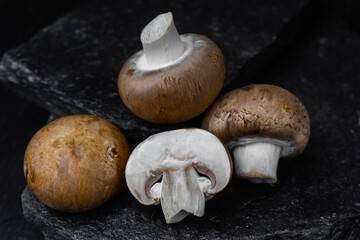Fresh white champignons on the dark kitchen table. Cooking delicious dishes with mushrooms