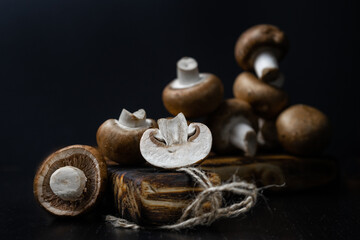 Fototapeta na wymiar Fresh white champignons on the dark kitchen table. Cooking delicious dishes with mushrooms