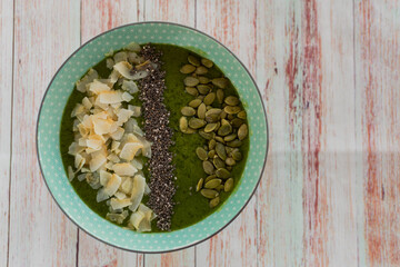 green smoothie bowl of vegetables and fruits with nuts. Vegan healthy breakfast. Top view
