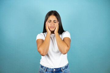 Young beautiful woman  standing over isolated blue background suffering from headache desperate and stressed because pain and migraine with her hands on head