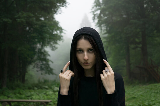 Young woman wear black hooded mantle in the misty forest - Powered by Adobe