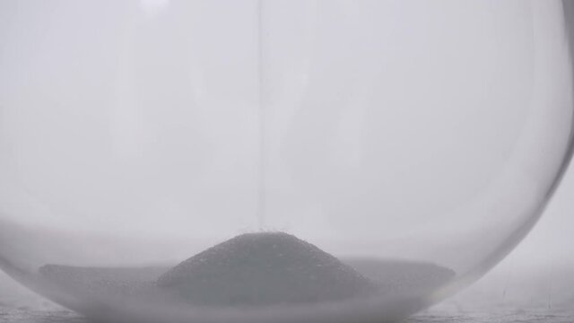 Macro close detail of sand pile pouring on bottom of hourglass