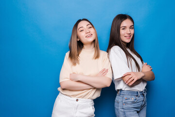 Fototapeta premium Two dissatisfied women posing isolated on yellow blue background. People lifestyle concept. Mock up copy space. Holding hands crossed