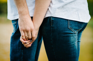 Cropped photo young married couple hugging, husband and wife holding hands on nature. lower half. Close Up. Hand swear, vintage style. Focus on hands. Summer in love.