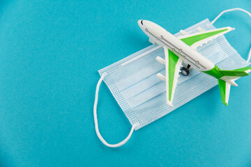 Safe travels concept. Plane with surgical medical mask. Safety flight and travel during quarantine and lockdown.