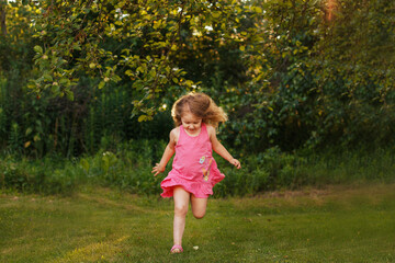 Naklejka premium happy baby smiling. little girl running at a sunset outdoor