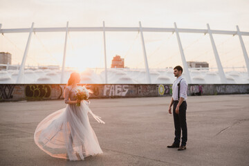 Romantic and happy caucasian couple in wedding clothes walking and hugging at the city streets. Love, relationships, romance, happiness, urban concept. Bride and groom celebrate their marriage.