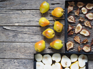 Space for text.Autumn harvesting.Dried and fresh pears in grates from the dryer with whole pears on a wooden background.