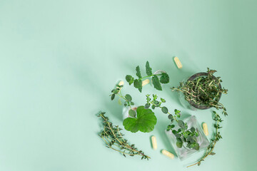 Alternative medicine, oregano, mint, thyme, herbs in a glass bottle on a green background. View...