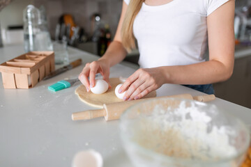 Woman's hands holding homemade yeast dough next to ingredients whole grain flour, eggs, water