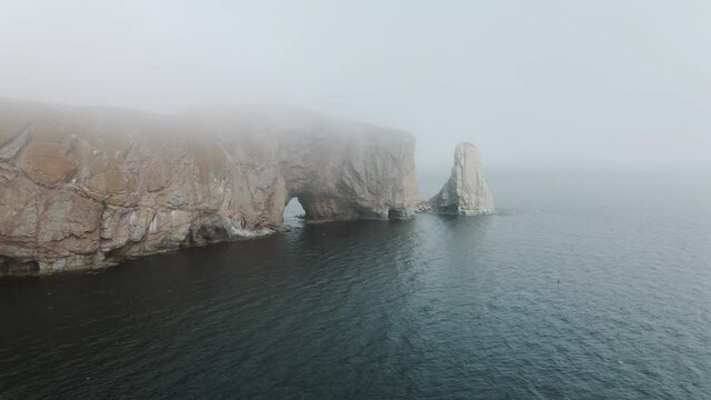 Perce Rock At The Gulf Of Saint Lawrence Near The Perce And Gaspe Peninsula  On A Foggy Day In Quebec, Canada.  -aerial drone