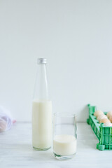 Fresh milk on glass bottle standing on the white background with eggs and glass