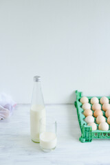 Fresh milk on glass bottle standing on the white background with eggs and glass