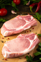 Fresh raw pork entrecote on the bone, a piece of pork with spices on a wooden board