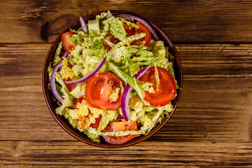 Vegan salad with savoy cabbage, tomatoes and onion in a ceramic bowl. Top view