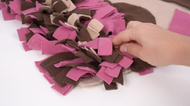 Owner checks and cleans a soft washable textile training snuffle mat for dogs nose work from wool and small debris before using, and hides snacks