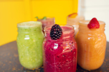 Colorful smoothies with fruit decoration on wooden table with yellow background. Healthy drinks concept. Healthy smoothies.