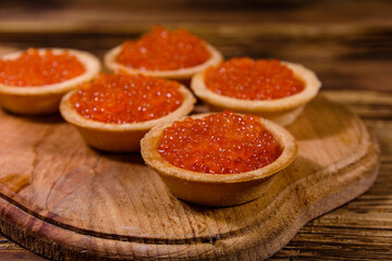 Tartlets with red caviar on a wooden cutting board. Festive food