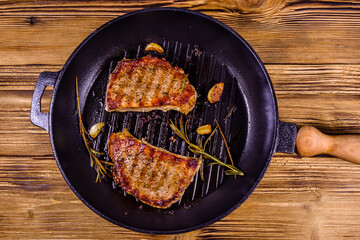 Roasted steaks with garlic, rosemary and spices in a cast iron grill pan. Top view
