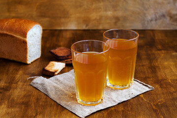 Cold drink. Two glasses of homemade bread kvass with black rye bread and hard chucks on a wooden table. Beer with sackcloth on brown background. summer soft drink.