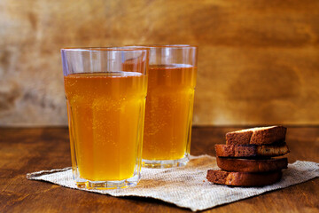 Two glasses of homemade bread kvass with black rye bread and hard chucks on a wooden table. Beer with sackcloth. summer soft drink. close-up