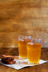Two glasses of homemade bread kvass with black rye bread and hard chucks on a wooden table. Beer with sackcloth. vertical. summer soft drink.