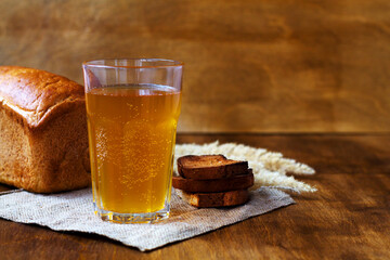 Glass of homemade bread kvass with black rye bread on a wooden table. Beer with sackcloth. copy space. summer soft drink.