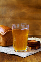 Glass of homemade bread kvass with black rye bread on a wooden table. Beer with sackcloth. vertical. summer soft drink.