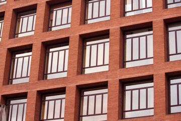 Urban texture and pattern. Architecture. Closeup view of the building facade. The apartment windows and the red brick wall.