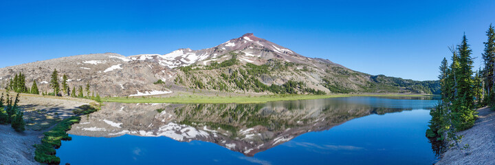 Fototapeta na wymiar Mountain landscape with clear blue sky, morning light, reflective water, and a wide panoramic view.
