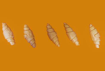 Golden croissants on an orange background. Place for text