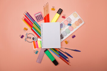 School notebook and various stationery on pink background. Back to school concept