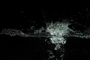 Water splashing as it's poured into aquarium tank, black background