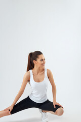 Fototapeta premium Pretty joyful young sportswoman in tracksuit standing and warming up isolated over grey background