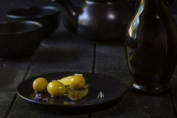 green olives on plate on black background