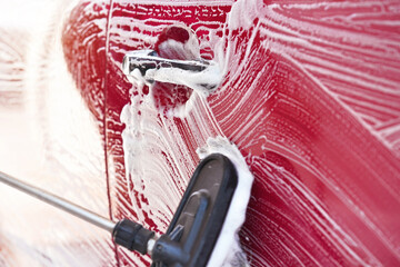 Red car washed in self serve carwash , detail on brush leaving strokes on side door, wide banner...