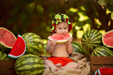 Baby girl sitting outdoors in summer and eating ripe watermelons. Harvesting