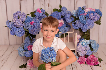 Happy baby boy in the studio on a white background with pink and blue hydrangea flowers