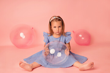 Happy baby girl on a pink background with balloons. Celebration. Birthday