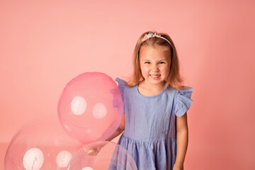 Happy baby girl on a pink background with balloons. Celebration. Birthday