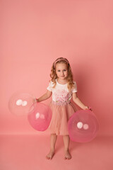 Happy baby girl on a pink background with balloons. Celebration. Birthday