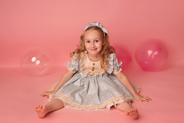 Happy baby girl on a pink background with balloons. Celebration. Birthday