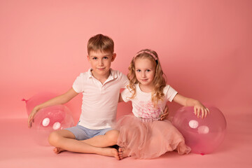 Happy child girl and boy on a pink background with balloons. Celebration. birthday