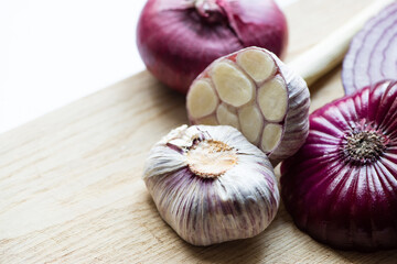 close up view of red onion and garlic on wooden cutting board isolated on white
