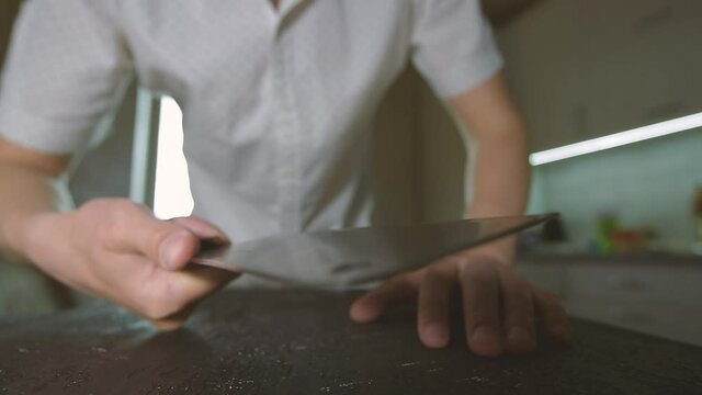 a kitchen knife in the cook's hand is sharpened in a special knife sharpener on the table.man sharpening knife