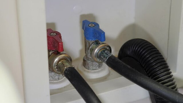 Plumber turning on cold water supply shut-off valve for clothes washing machine.