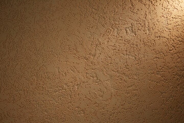 Structural background with patterns in dark cream color illuminated by a short beam