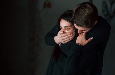 Man's hand covering her mouth. Kidnapped woman is threatened by guy